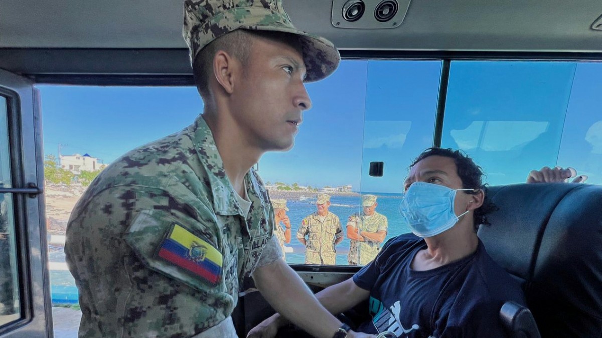 În imagine este ilustrat un bărbat în uniformă militară care îi ia tensiunea unui bărbat care poartă mască.