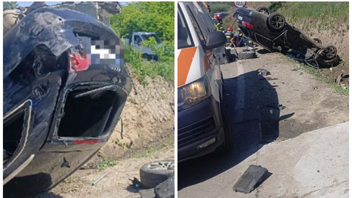 În imagine se văd urmările unui accident rutier grav: un autoturism răsturnat pe plafon pe marginea unui drum, cu avarii majore în partea din spate. În jurul mașinii sunt împrăștiate mai multe fragmente auto și obiecte, iar în partea dreaptă apare o ambulanță.