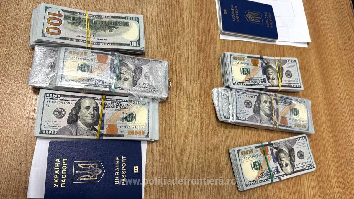 60.000 de dolari în hârtii de câte 100 de dolari, așezate pe o masă din lemn maro, lângă două pașapoarte de Ucraina