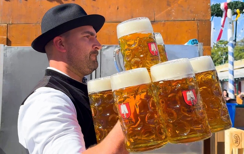 Chelner care transportă halbe de bere la Oktoberfest, München, Germania, 21 septembrie 2024.