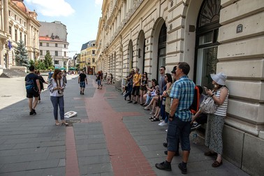 Lângă sediul Băncii Naționale, Cătălina le vorbește oamenilor din grup despre bacnotele romănești din plastic și le povestește , într-un mod interactiv, despre fiecare personaj imprimat pe ele