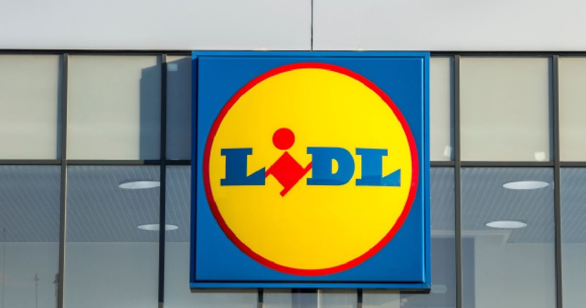 Fotografie cu logo-ul supermarketului Lidl, montat pe o clădire modernă cu ferestre mari din sticlă.
