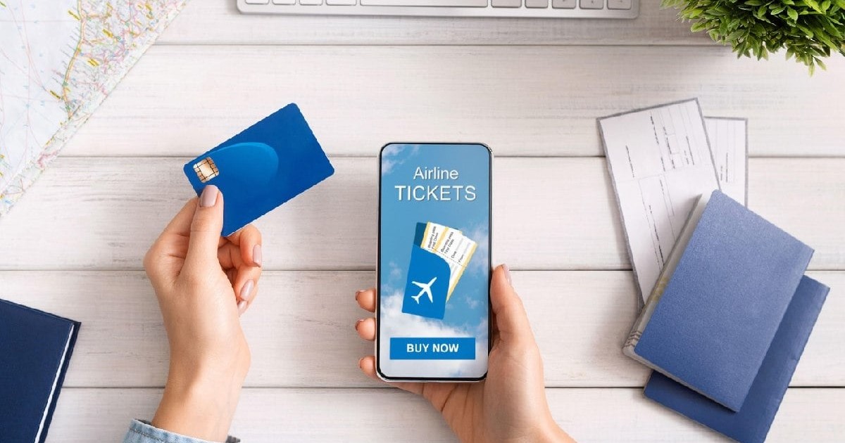 Femeie care își rezervă bilete de avion online, folosind un card bancar și un telefon mobil.