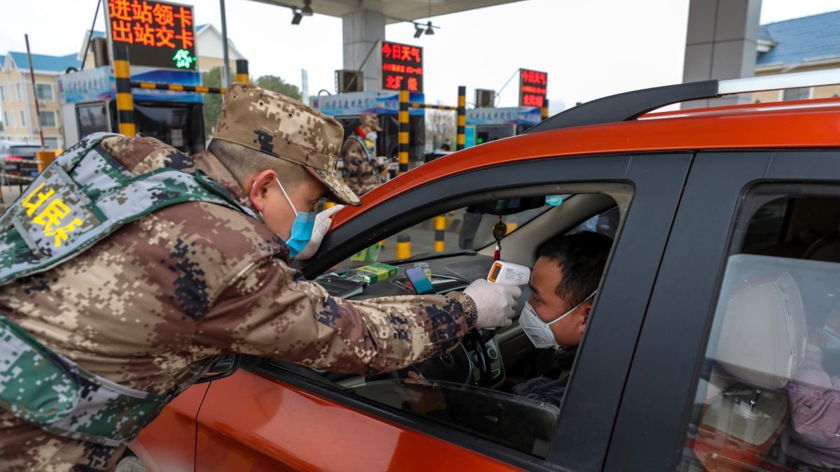 Un polițist verifică temperatura unui șofer, în Wuhan, China, orașul intrat în carantină din cauza epidemiei FOTO: EPA