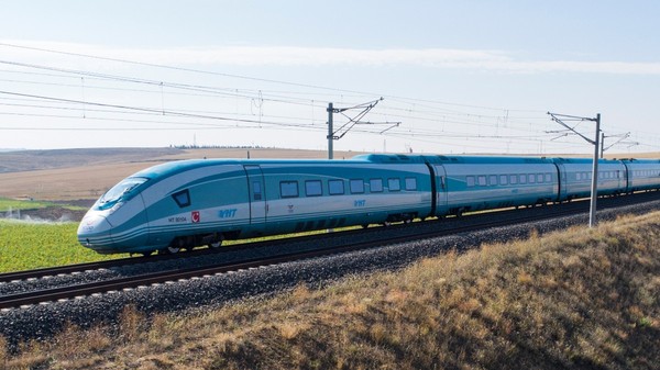 Un tren de mare viteză al căilor ferate turcești (YHT) deplasându-se pe o cale ferată prin zone rurale uscate.