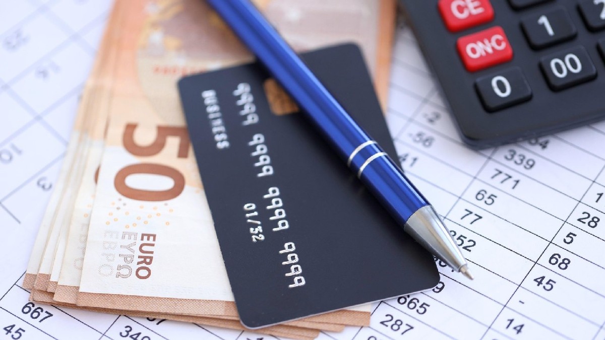 Card de credit și stilou cu bancnote în euro pe fundalul unui document de calcul.
