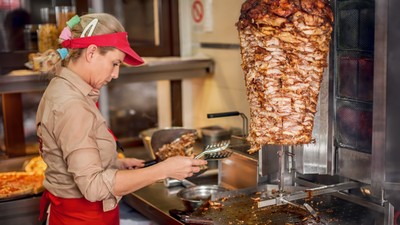 Chef preparing roasted sliced gyros meat in fast food restaurant