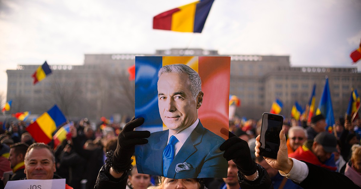 O femeie tine in maini o fotografie a lui Calin Georgescu