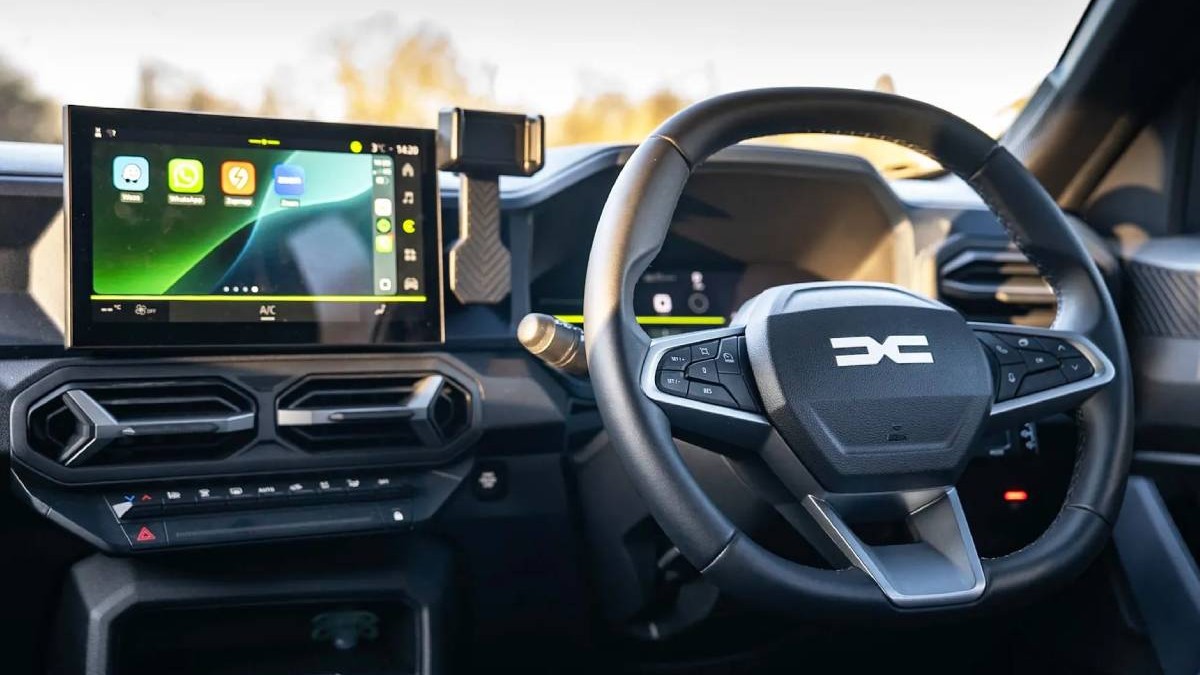 interior masina electrica dacia duster, pe volan se observa noul logo dacia, se observa consola centrala touchscreen