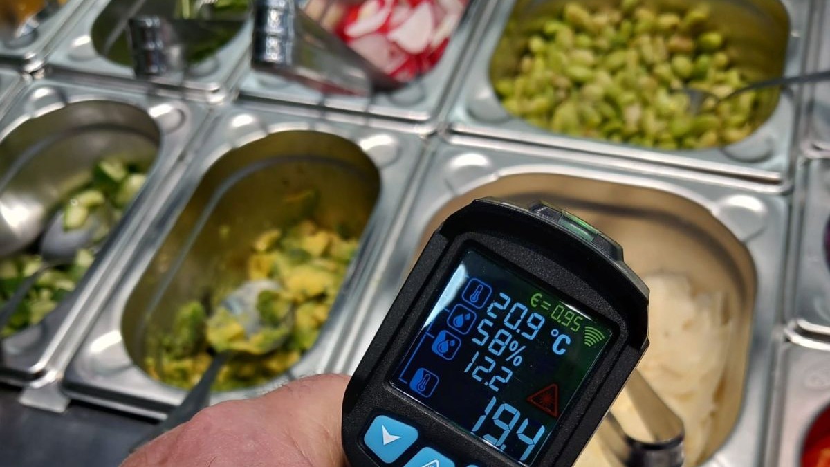 Un bărbat de la ANPC, cu un termometru în mână, măsoară temperatura mâncărurilor dintr-un restaurant, Timișoara, 28 martie 2025