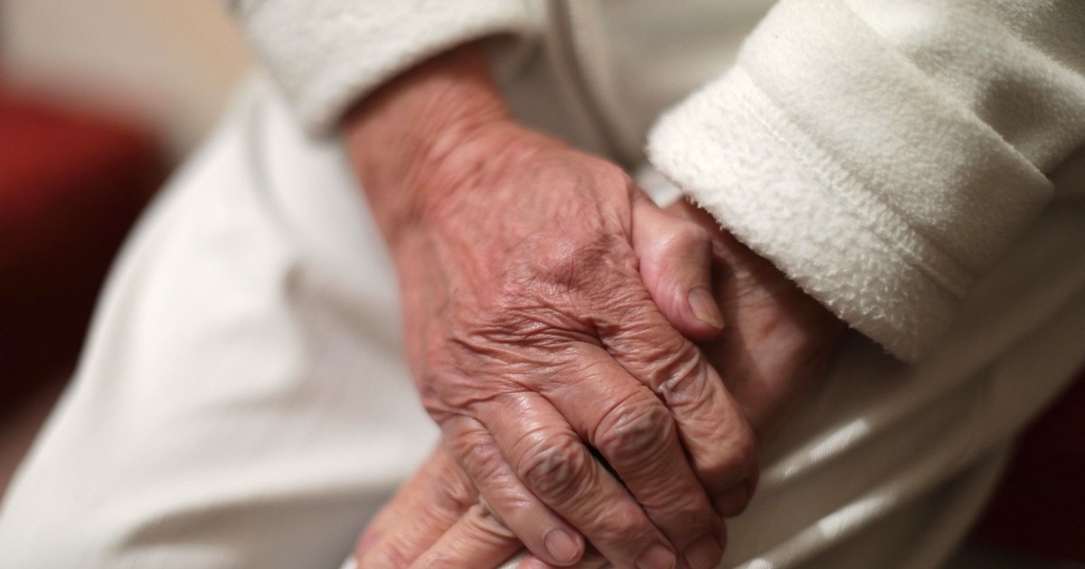 Mâinile unei paciente cu Parkinson, așezate pe picior