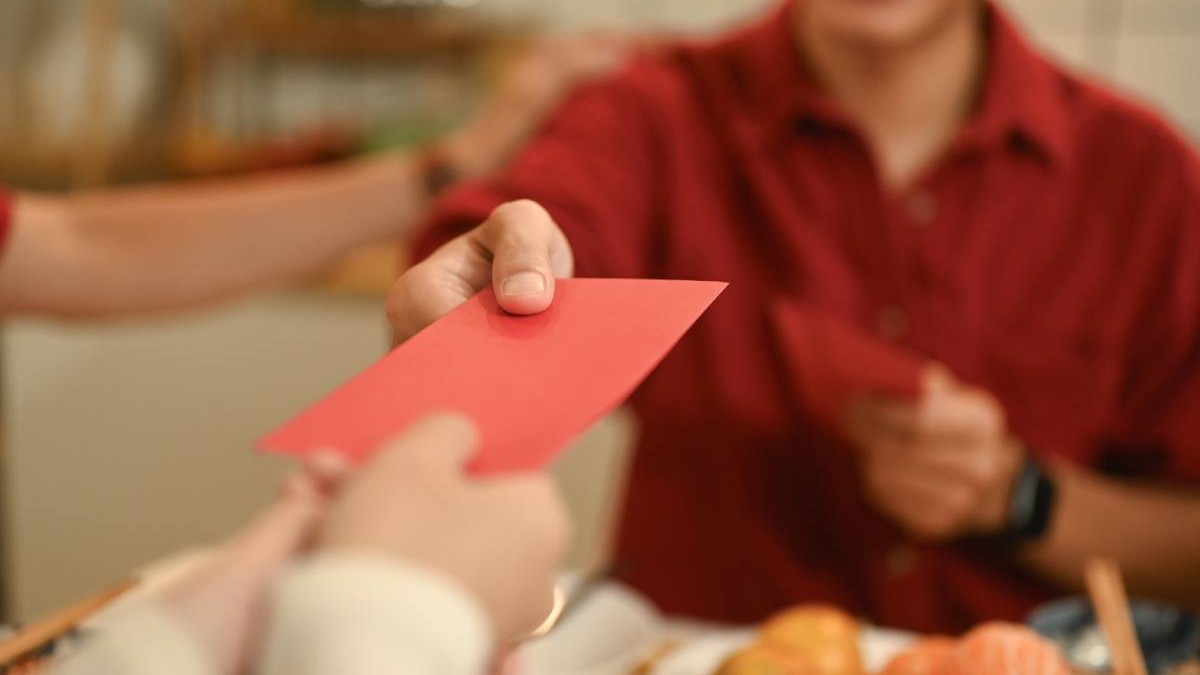 Prim-plan cu o mână care oferă un plic roșu sau un Hongbao în timpul sărbătorii festive a Anului Nou Chinezesc