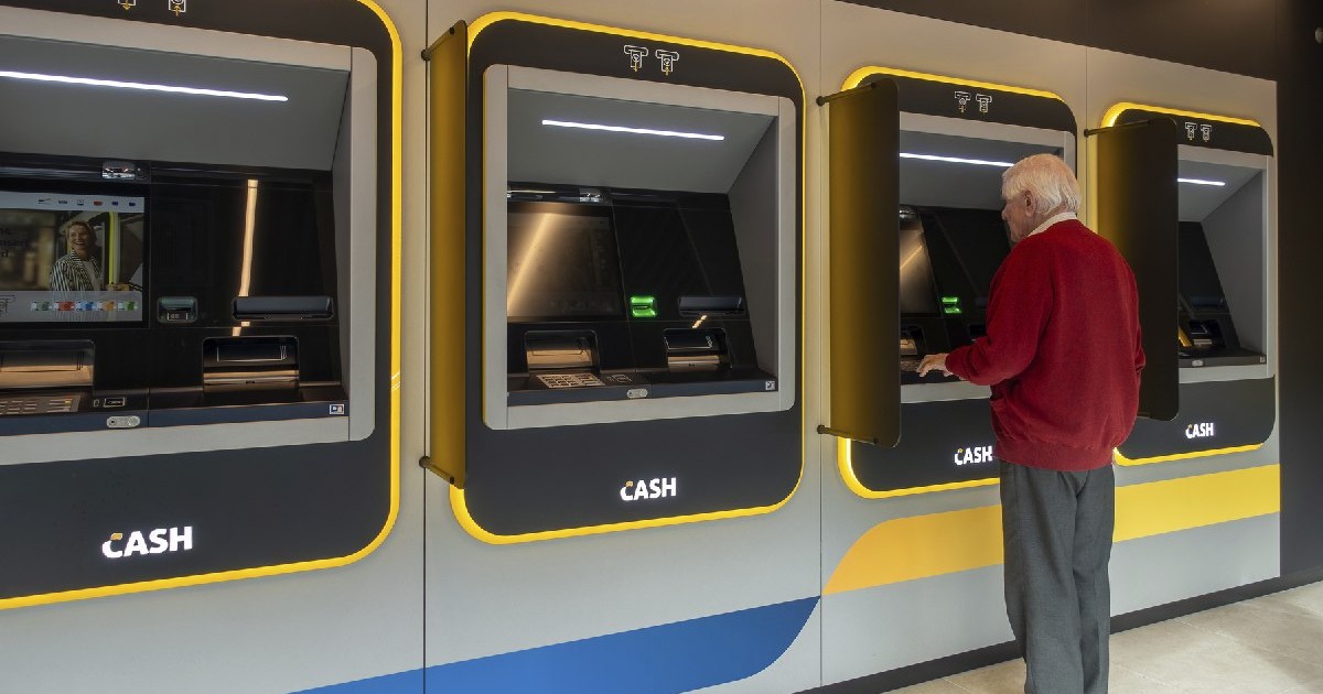 Bărbat în vârstă care retrage bani de la un bancomat interior al băncii Bancontact CASH din Flandra, Belgia.