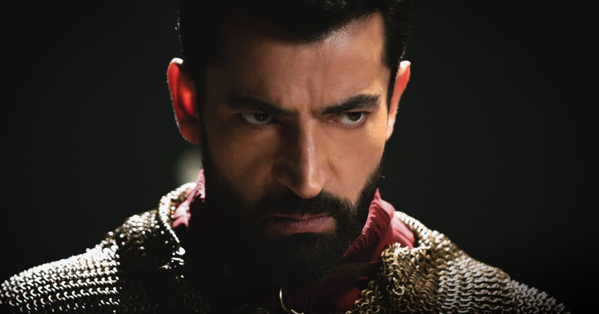 Prim plan cu actorul Kenan İmirzalıoğlu, pe fundal negru, semi-intunecat