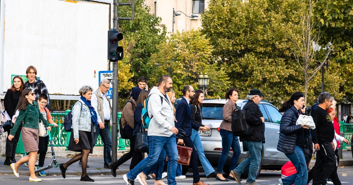Mai mulți oameni traversează o stradă din București