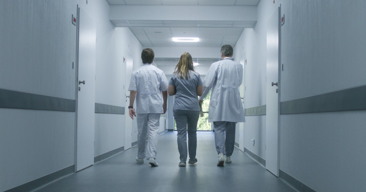 Trei doctori care merg pe coridorul unui spital
