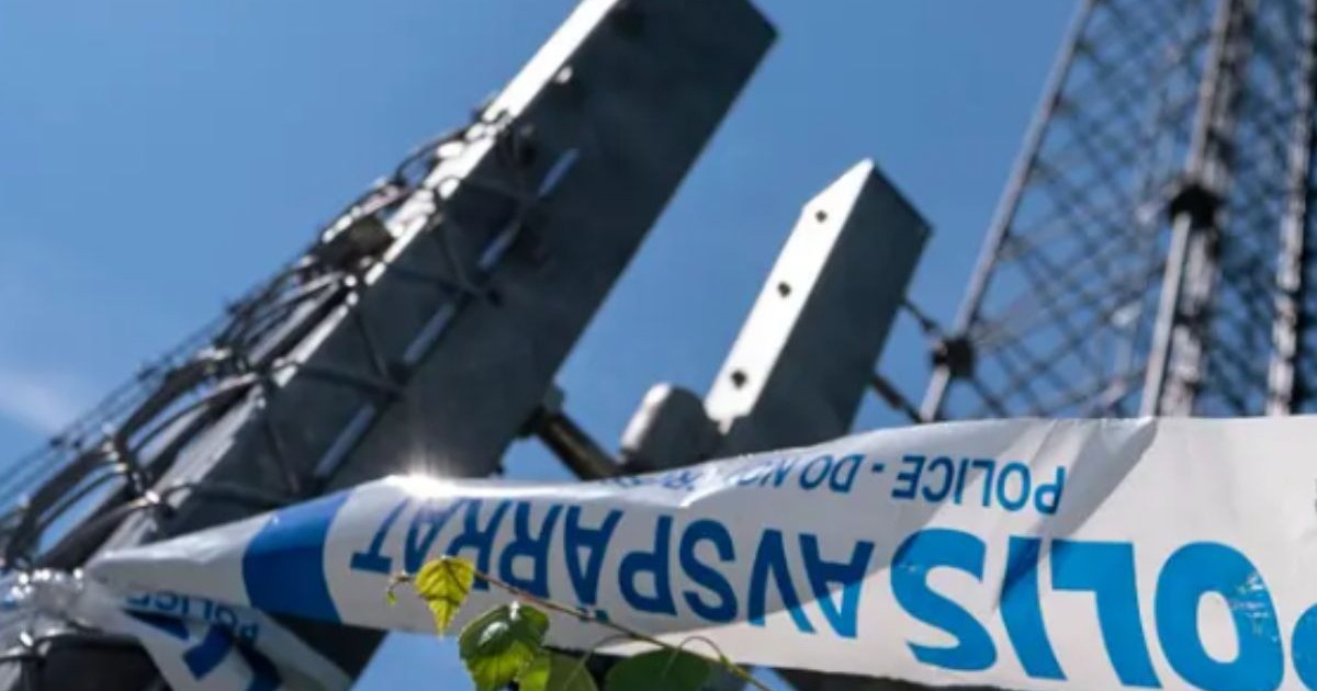 Imagine de jos cu niște turnuri de telecomunicații sub un cer albastru, in prim plan o bandă alb cu albastru cu scris pe ea, conceptul de sabotaj în telecomunicații