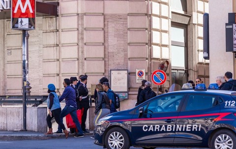 O mașină de Carabinieri oprită în dreptul unei stații de metrou din Milano, mai mulți turiști în haine groase coboară pe scările de la metrou