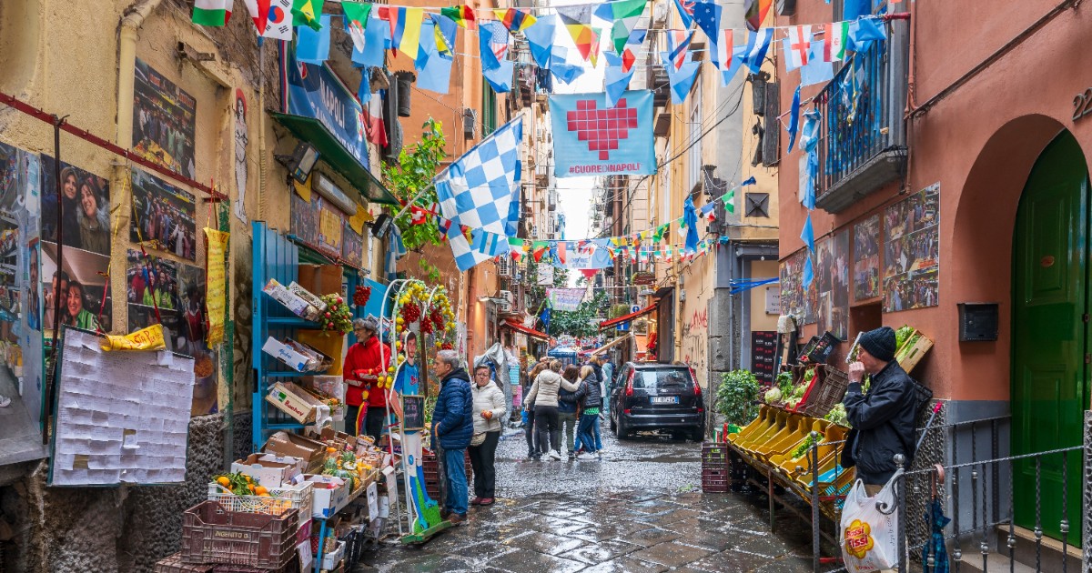 O stradă aglomerată din Napoli, unde turiștii se plimbă pe la magazine și tarabe