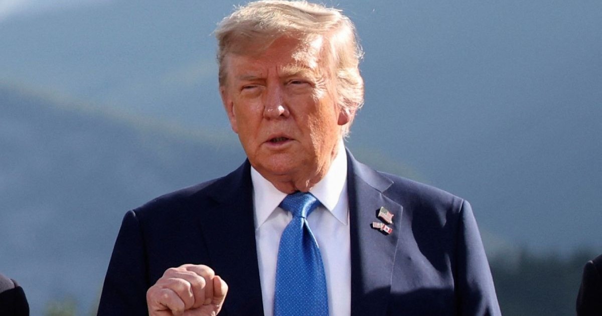 Donald Trump in sacou si cu cravata, si cu mana dreapta ridicata la nivelul pieptului si punemul strans