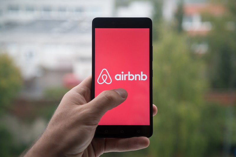 Airbnb și Booking, interzise în România prin legea turismului. Proiectul a fost adoptat tacit de Senat și ajunge în Camera Deputaților. Airbnb pe un smartphone