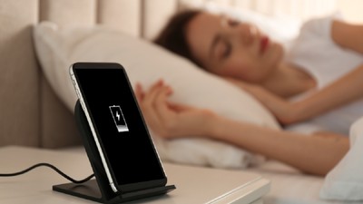 Imagine cu o femeie care doarme lângă un telefon aflat la încărcat