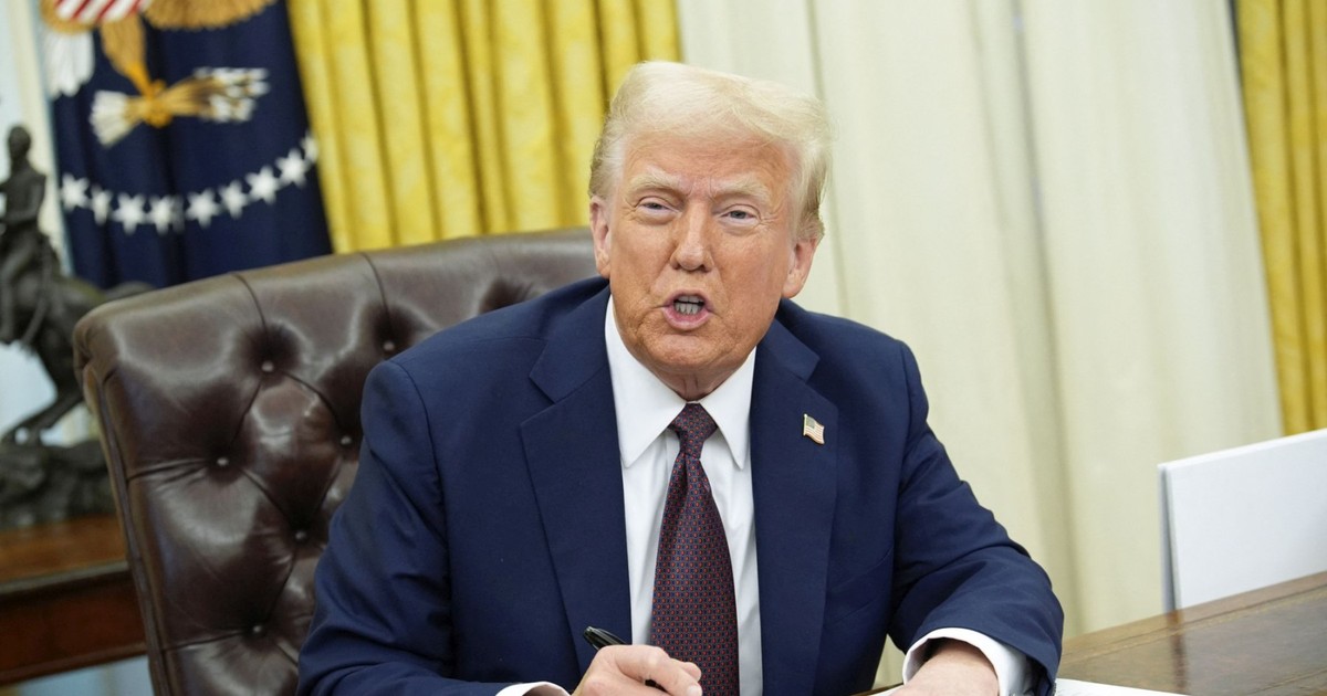 Donald Trump este cu stiloul în mână și semnează niște acte la biroul de la Casa Albă