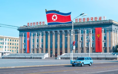 Pyongyang, Coreea de Nord – octombrie 2019 O mașină veche albastră circulând pe o stradă din Pyongyang, cu steagul Coreei de Nord