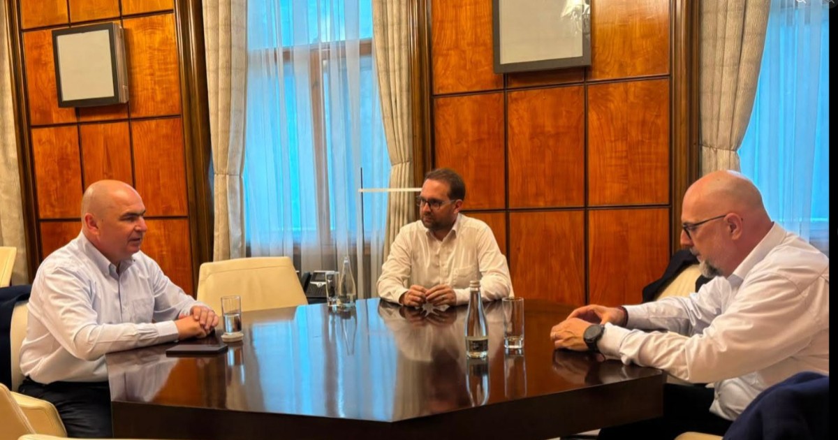 Ilie Bolojan, Dominic Fritz și Kelemen Hunor care stau la o masă și discută.