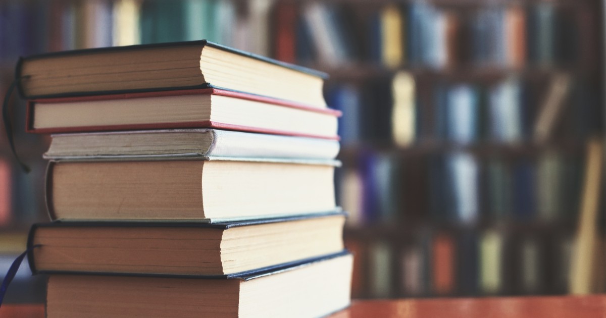 Șase cărți așezate pe un birou, într-o bibliotecă.