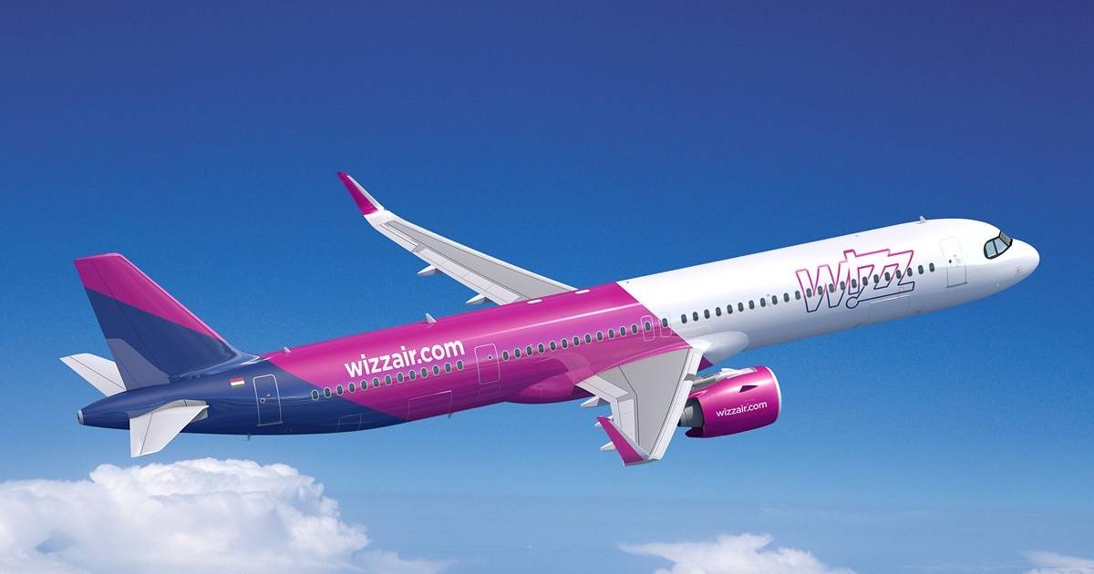 avion care apartine companiei wizz air, modelul Airbus A321neo. fuselajul este vopsit în culorile specifice companiei: roz, violet și alb.