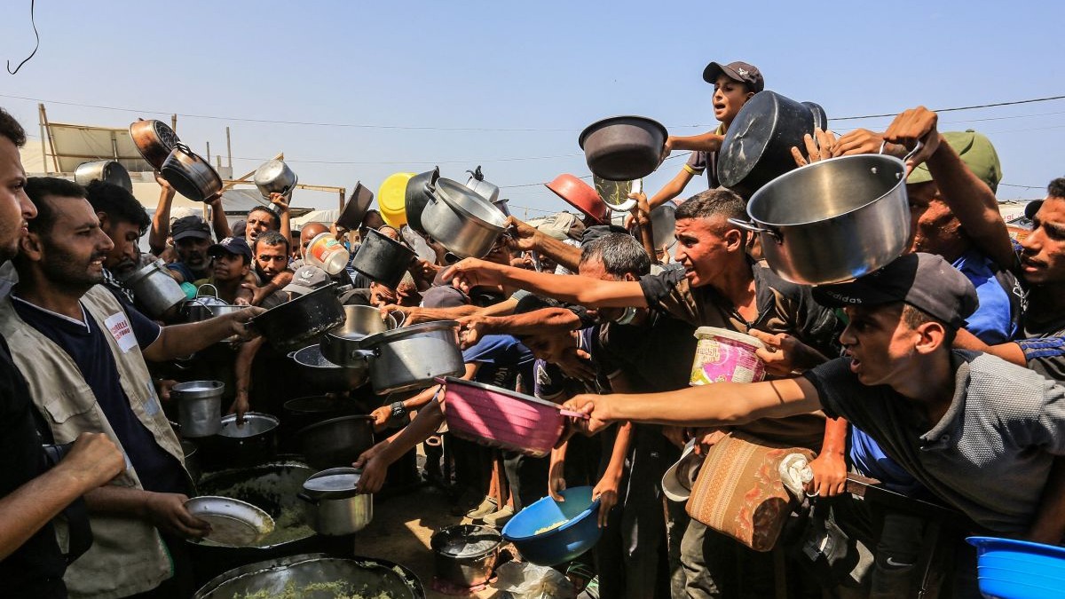 Palestinieni care se luptă cu foametea se adună în jurul unei organizații caritabile turcești care distribuie mâncare în zona Al-Mawasi din Khan Yunis, Gaza, august 2025