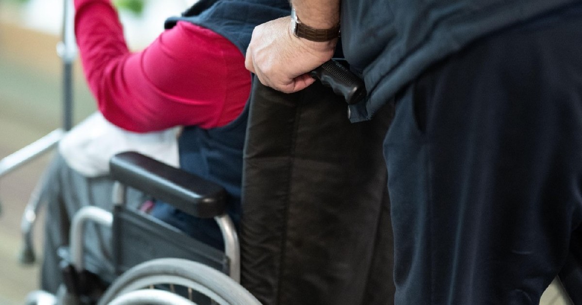 Vedere parțială a unei persoane care ajută pe cineva într-un scaun cu rotile