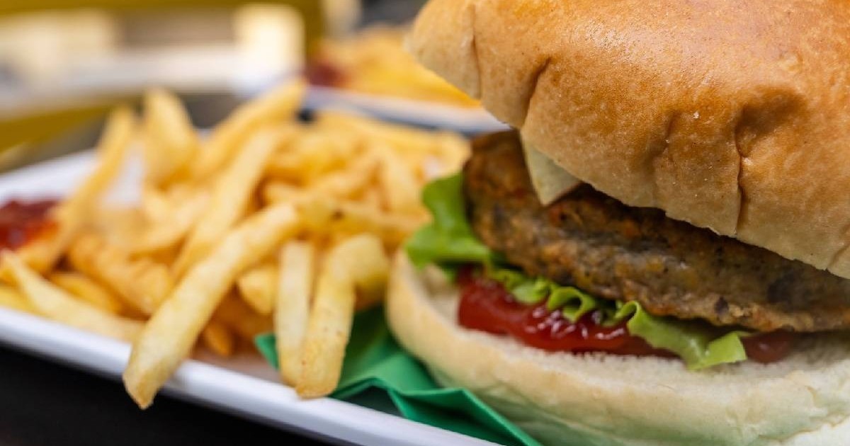 Un burger ;i cartofi pr[ji'i pe o farfurie albă