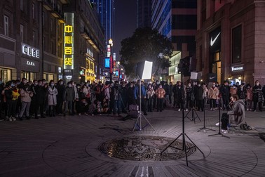 Locuitorii din Wuhan ascultă un artist stradat, în Wuhan, la un an de la lockdown FOTO: EPA