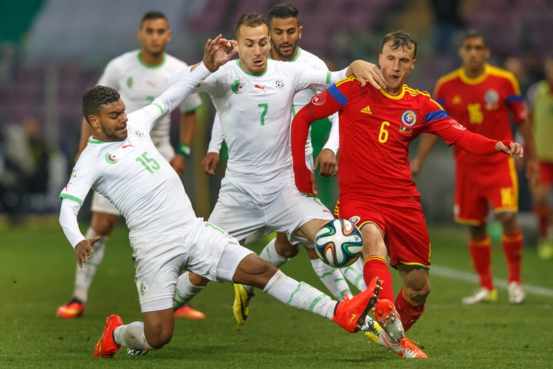epa04240038 Romania's Vlad Chiriches, right, fights for the ball with Algeria's players Bogdan Mitrea, left, and Hassan Yebda, centre, during an international friendly test match between the national soccer teams of Algeria and Romania, at the Stade de Geneve stadium, in Geneva, Switzerland, 04 June 2014. EPA/SALVATORE DI NOLFI