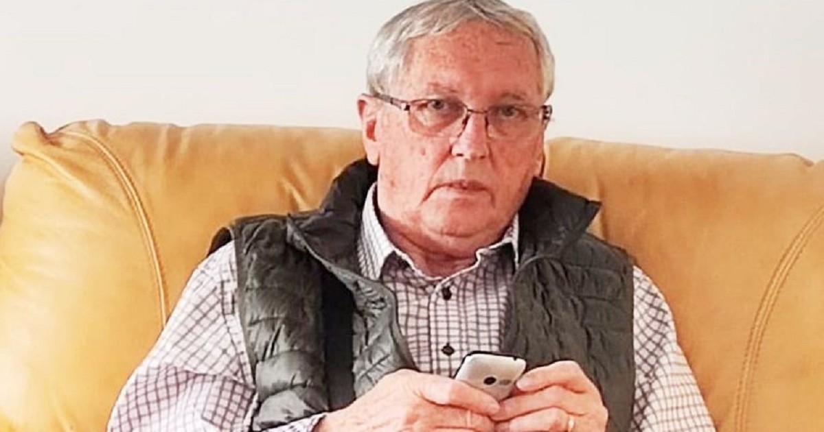 Emeric Dembrovschi stă pe o canapea, în mână ține un telefon mobil