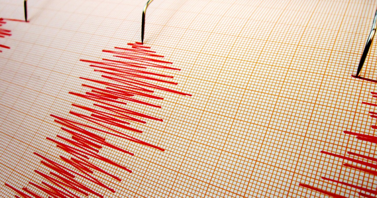 Imaginea arată un seismograf, dispozitiv care înregistrează undele produse de un cutremur, cu linii roșii ce indică intensitatea și durata mișcărilor seismice pe o hârtie milimetrică