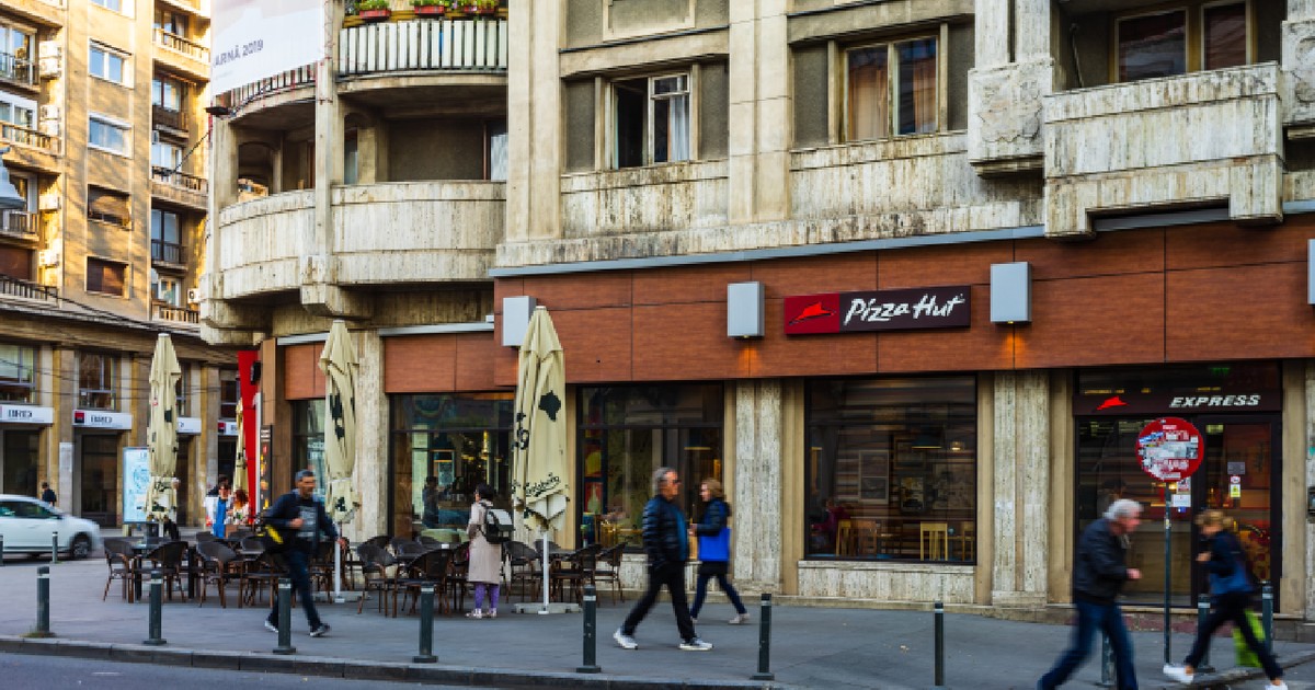 Pietoni mergând în fața restaurantului Pizza Hut din București, România, 2019