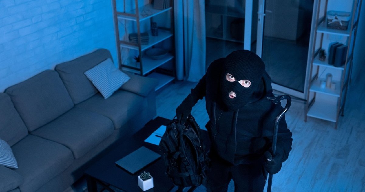 O camera de supraveghere a surprins momentul în care hoțul mascat pătrunde în apartament și se uită în sus.