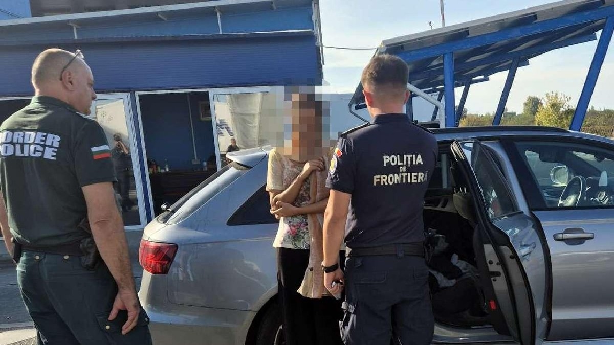 Doi polițiști de frontieră, unul din Bulgaria si unul din România, discută  cu o femeie langa o masina gri, la vama Calafat