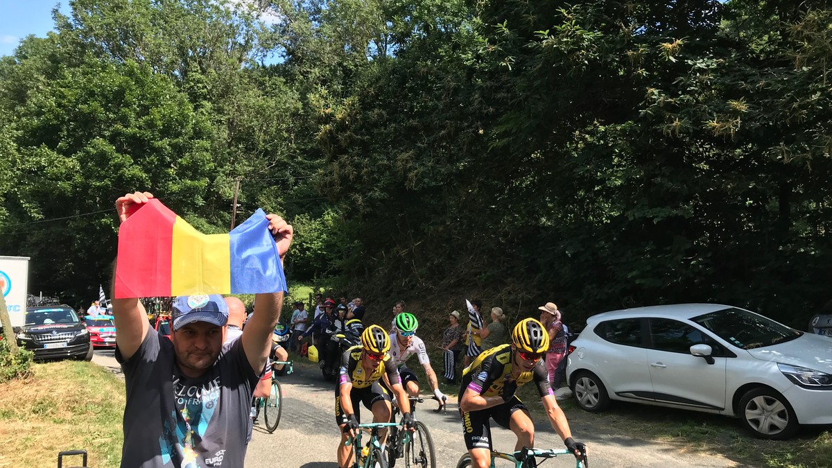 Cicliștii în cursă trec pe lângă reporterul Libertatea care flutură steagul României.