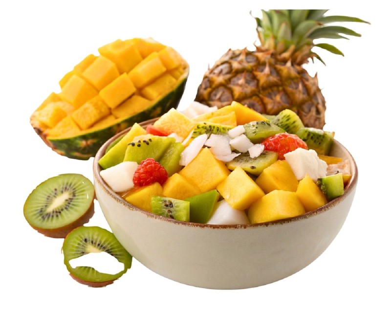 Salată colorată de fructe într-un bol alb, lângă un mango tăiat grilaj și un ananas întreg.