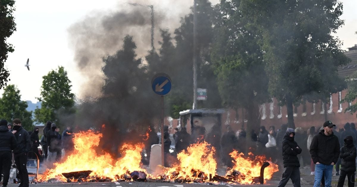 Mai mulți tineri se strâng în fața unei baricade în flăcări în Grădinile Duncairn, pe 9 iunie 2026, în Belfast, Irlanda de Nord
