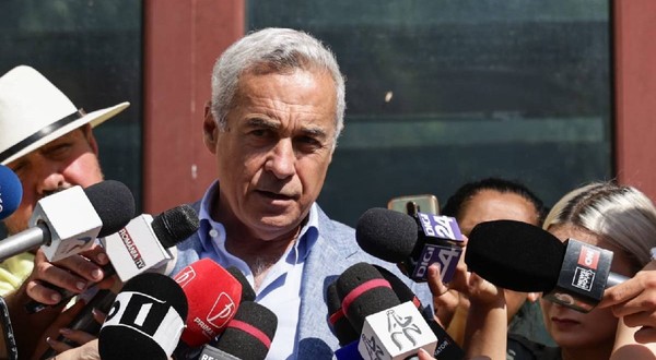 Călin Georgescu vorbește cu jurnaliștii la ieșirea din Parchet. e îmbrăcat cu un costum și are o figură gravă