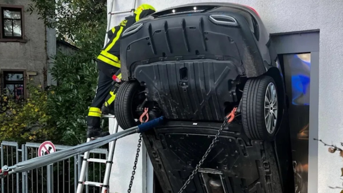 O mașină blocată vertical într-un lift în timp ce un pompier intervine