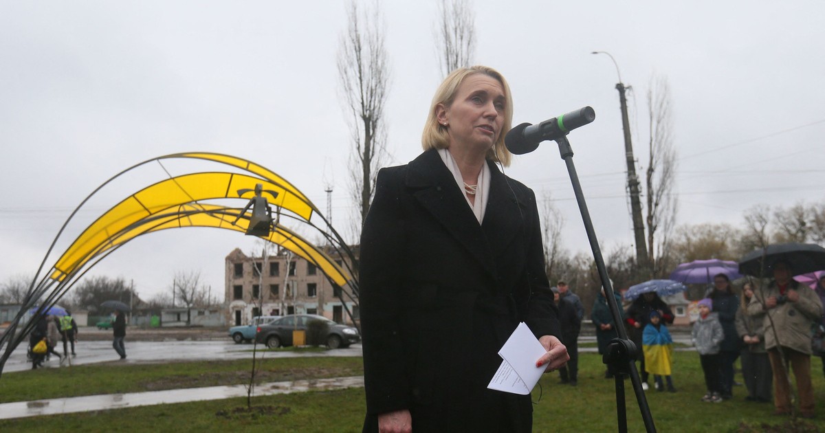 o femeie blondă vorbește la un microfon într-un parc