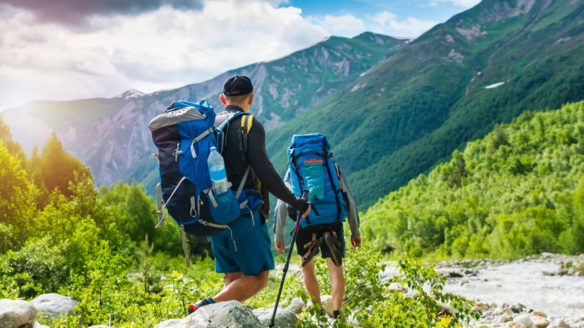 Ce reguli trebuie să respecţi când mergi la munte - Imagine cu doi turişti cu rucsacuri amri în spate pe o cărare de munte.