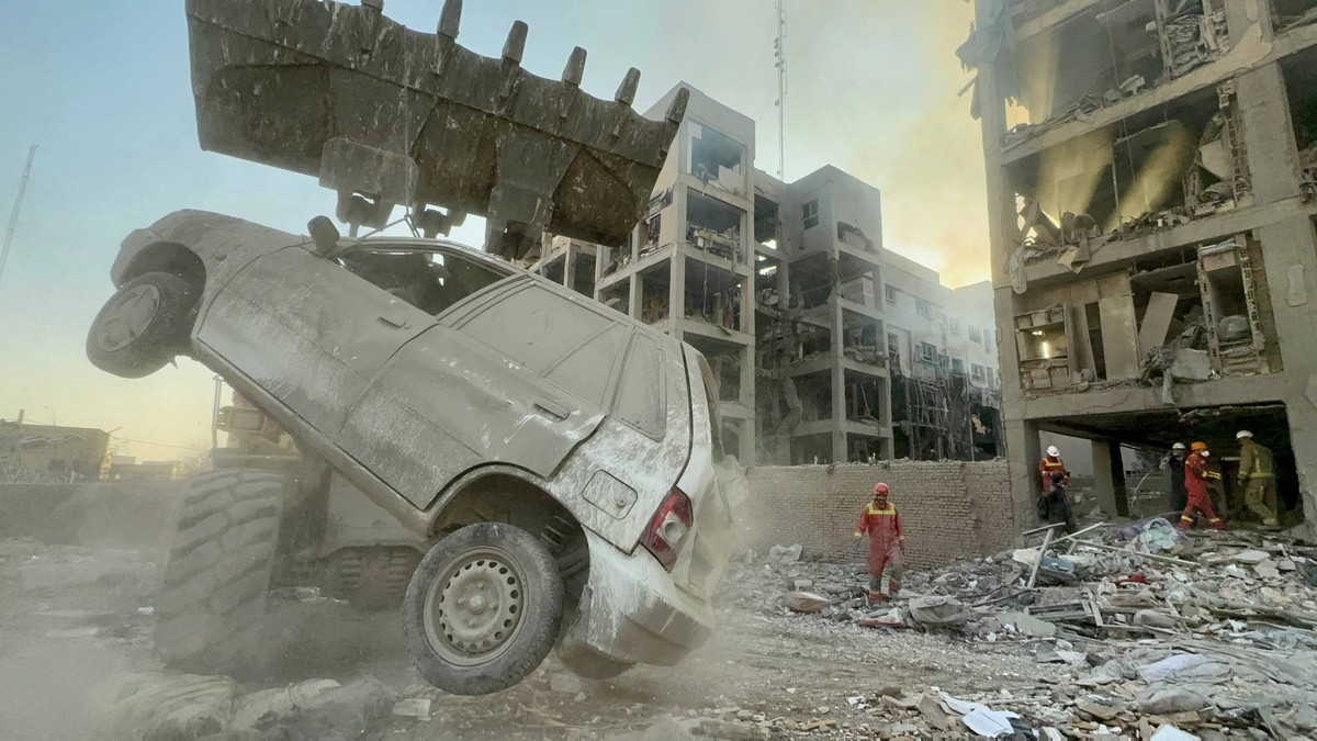 Rămășițele unei clădiri bombardate în Iran, o mașină este ridicată în prim plan.