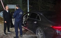 Un bărbat în trening negru, cu fața blurată. Acesta se află lângă un polițist